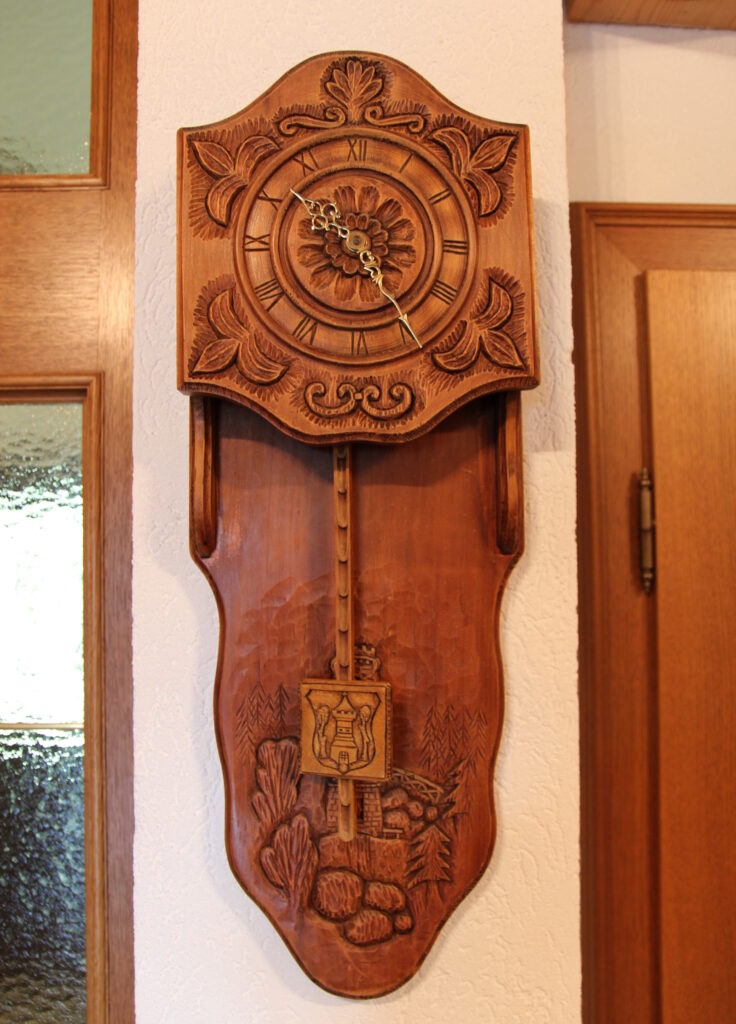Große Pendeluhr aus Holz mit diversen geschnitzten Motiven darauf